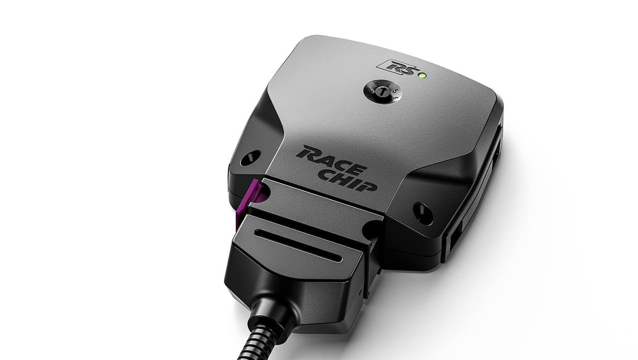 RaceChip RS Steuergerät in schräger Liegeposition auf weißem Hintergrund, mit sichtbarem grünen Betriebslicht und violettem Clipverschluss.